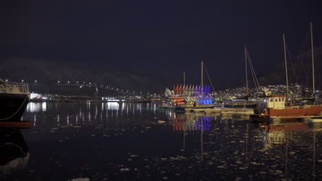 Weitwinkelaufnahme-Von-Schiffen-Im-Hafen-Und-Der-Berühmten-Brücke-Im-Hintergrund-Bei-Nacht-In-Tromsø,-Norwegen