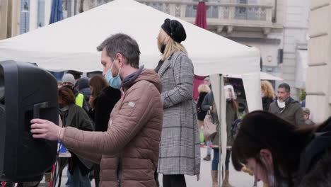 Mujer-Rubia-Enmascarada-Habla-Con-Personas-Leyendo-Un-Periódico-Durante-La-Protesta-En-La-Plaza-De-Milán-En-Enero