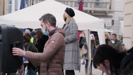 Eine-Maskierte-Blonde-Frau-Spricht-Während-Der-Proteste-Auf-Dem-Mailänder-Platz-Im-Januar-Mit-Leuten,-Die-Eine-Zeitung-Lesen