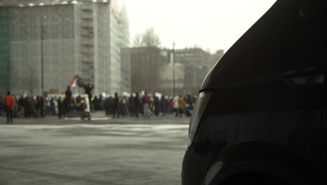 Wide-shot-of-the-crowd-of-protesters-gathered-for-the-covid-19-protests-in-Helsinki,-black-car-in-shot