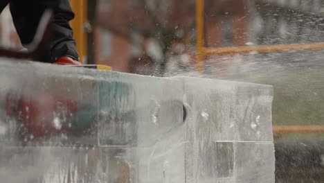 Static-shot-of-electric-chainsaw-blade-cutting-through-large-ice-block,-Slow-motion