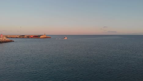 Boat-leaving-port-at-sunset.-Aerial-forward