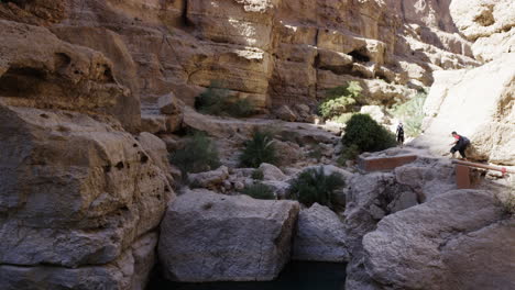 Hikers-around-the-pools-of-Wadi-Shab-canyon,-Oman,-handheld-wide-shot