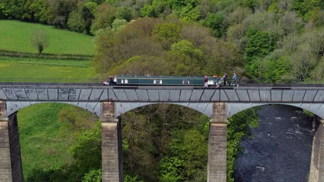 Luftaufnahme,-Die-Einem-Schmalen-Boot-Auf-Der-Überquerung-Des-Pontcysyllte-Aquädukts-Im-Trevor-Becken-In-Der-Walisischen-Tallandschaft-Folgt