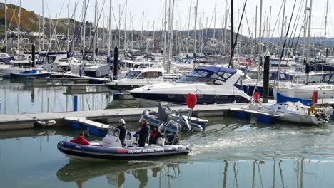Racing-sports-team-dinghy-boat-cruising-through-sunny-Conwy-marina-luxury-yachts-boating-waterfront