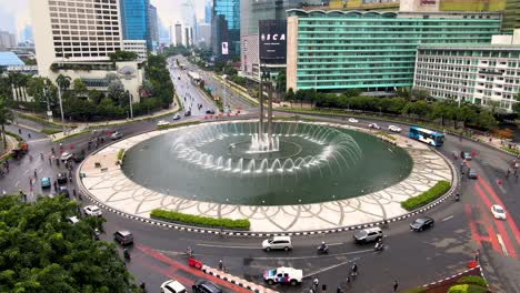 Sunday-traffic-on-roundabout-by-Selamat-Datang-Monument-in-Jakarta,-aerial-view
