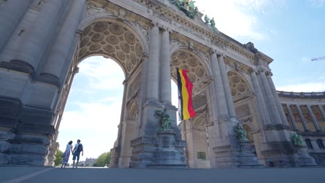 Upwards-angle-backwards-dolly-shot-of-the-Cinquantennaire-triumphal-arc-monument-in-Brussels,-Belgium,-on-warm-sunny-summer-day-with-blue-skies