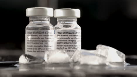 Two-Bottles-Of-Covid-Vaccine-Made-By-Pfizer-With-Melting-Ice-Cubes-On-Foreground