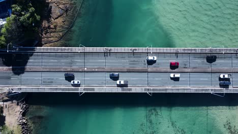 Küstenstraße-Und-Fußgängerbrücke,-Die-Eine-Klare-Meeresmündung-überspannt-Und-Menschen-Und-Fahrzeugen-Die-Überquerung-Ermöglicht
