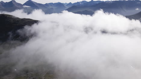 Low-thick-clouds-over-the-green-mountain-landscape-of-Romsdalen,-Norway--Aerial