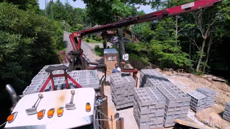 Aerial-zoom-into-cubes-of-concrete-and-cinder-blocks-being-unloaded-at-construction-jobsite
