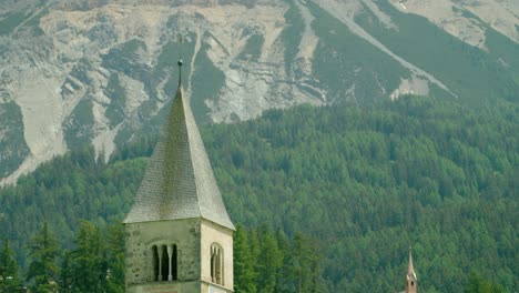 Fokusaufnahme,-Malerische-Aussicht-Auf-Die-Spitze-Des-Kirchturms-In-Italien,-Im-Hintergrund-Die-Felsige-Bergkette-Von-Melcesine