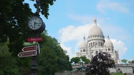 Schwenken-Sie-über-Die-Basilika-Sacre-Coeur-Mit-Sich-Drehendem-Karussell,-Einer-Vintage-Uhr-Und-Blauem-Himmel-Im-Hintergrund-In-Paris,-Frankreich