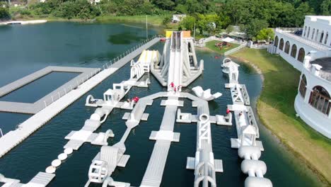 People-enjoying-a-sunny-day-at-Hong-Kong-core-aqua-park-floating-fun-slides,-Aerial-view