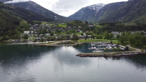Beautiful-seaside-aerial-of-Kinsarvik-town-centre-with-marina,-beach,-river,-camping-and-mountains---Hardanger-Norway