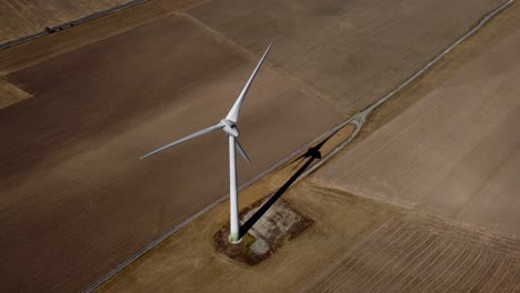Overhead-orbit-shot-of-single-wind-turbine-spinning-in-wind,-midday
