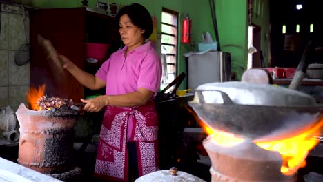Female-chef-roasting-goat-satay-on-charcoal-stove-traditional-Indonesian-dish