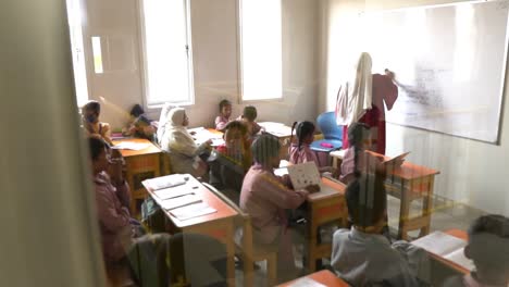 Profesora-Musulmana-Limpiando-La-Pizarra-En-El-Aula-Con-Niños-En-Pakistán