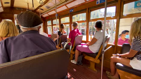 Tourists-in-protective-face-masks-sightseeing-Lisbon-downtown-streets-during-vintage-tram-tour-daytime