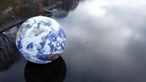 Luke-Jarram-floating-earth-exhibition-aerial-view-at-Pennington-flash-park-lake-descending-tilt-up