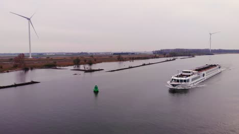 Luftaufnahme-Eines-Flusskreuzfahrtschiffs,-Das-Entlang-Der-Oude-Maas-Fährt-Und-An-Stillen-Windkraftanlagen-In-Barendrecht-Vorbeifährt