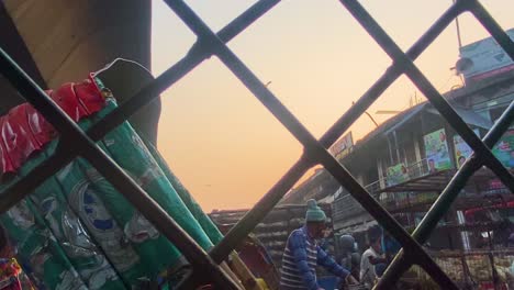 Orange-Sunset-View-Through-Wire-Fence-Of-Market-Chicken-Traders-On-Rickshaw-Carts-In-Dhaka