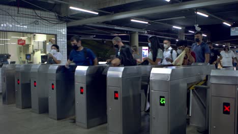 Passengers-entering-the-metro-station-at-the-turnstile-wearing-face-masks-at-rush-hour---time-lapse
