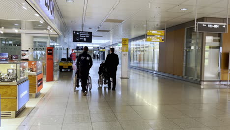 Ancianos,-Pasajeros-Discapacitados-Empujados-En-Sillas-De-Ruedas-En-El-Aeropuerto-De-Munich,-Viajes-De-Personas-Mayores,-Viajes-De-Personas-Mayores