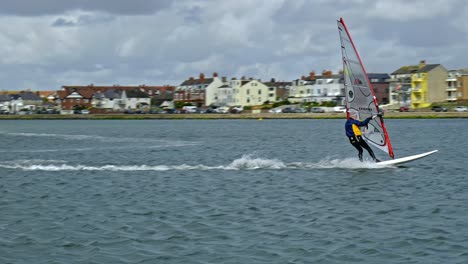 Hombre-Balanceándose-En-Una-Tabla-De-Surf-En-Clima-Ventoso-Practicando-Habilidades-De-Windsurf-En-El-Lago-Del-Puerto-Deportivo-De-West-Kirby