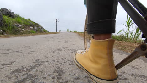 Close-up-of-a-feet-pedaling-in-a-bicycle-on-a-pavement-road