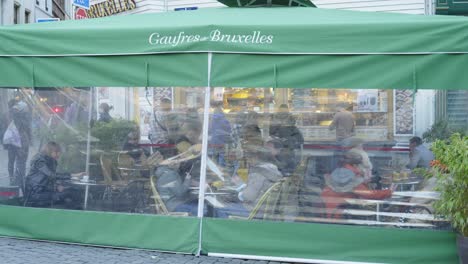 People-eating-Belgian-Waffles-in-outside-waffle-restaurant-passing-by-tourists-walking-through-the-downtown-wearing-protective-masks-against-coronavirus
