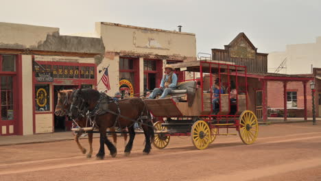 Horse-drawn-carriage-with-tourists-riding-through-town,-Tombstone-Arizona