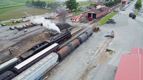An-Aerial-View-of-an-Antique-Steam-Passenger-Train-Waiting-for-a-Second-Steam-Train-To-Pass-Blowing-Smoke
