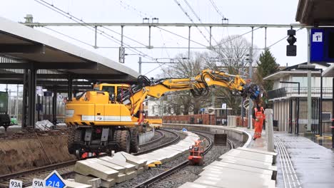 Large-mechanical-arm-doing-maintenance-and-construction-work-on-train-tracks-in-Zutphen-with-heavy-machinery-putting-large-blocks-in-its-place