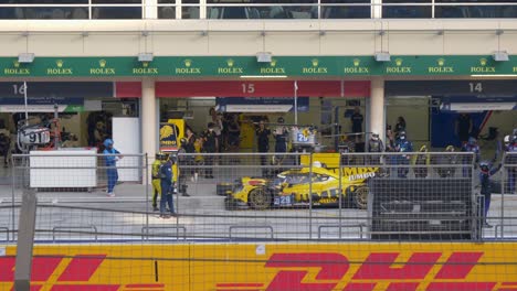 Cameraman-Filming-Pit-Crews-Changing-Tires-Of-Yellow-Sports-Car-In-Seconds-At-The-Pit-Stop