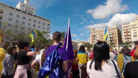 People-holding-up-flags-at-rally-against-war-in-Ukraine-on-clear-day