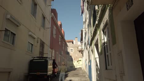 Kind-Beobachtet-Rolleranhänger,-Der-Die-Enge-Gasse-Von-Lissabon-In-Portugal-Hinauffährt