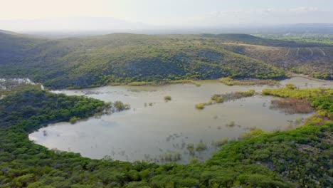 Panoramic-Mountainous-Aerial-View-as-Sunlight-Reflects-on-Mangrove-Forest-Waters,-Azua-Province,-Dominican-Republic