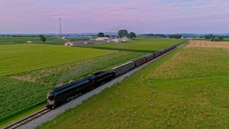 An-Aerial-View-of-a-Steam-Train-Approaching-Flying-Ahead-Traveling-Thru-Farmlands-and-Corn-Fields-Blowing-Smoke-on-a-Sunny-Summer-Day