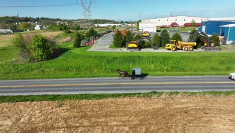 Rotierende-Luftaufnahme-Eines-Amish-Pferdes-Und--Buggys,-Das-Auf-Einer-Landstraße-Vorbeigefahren-Wird