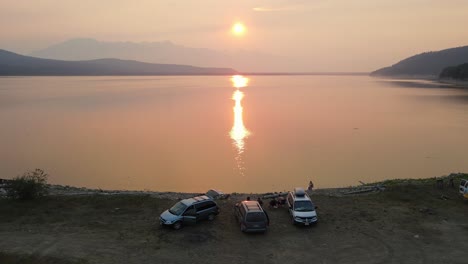 Three-cars-parked-at-a-campsite-on-Kinbasket-Lake-looking-out-towards-the-Rocky-Mountains-during-wildifres-in-Canoe-Reach-near-Valemount,-British-Columbia-Canada
