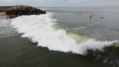 Surfer-Reitet-Auf-Einer-Küstenwelle-Und-Fällt-Ins-Wasser,-Luftaufnahme