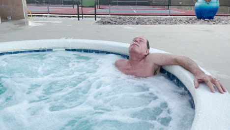 Elderly-man-relaxes-in-whirl-pool-spa-outdoors-at-hotel-resort