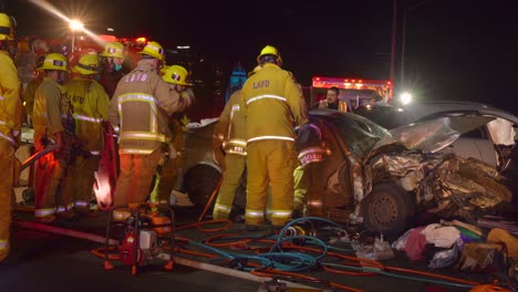 Los-Angeles-fire-department-saving-a-life-from-a-crashed-car,-during-night-time