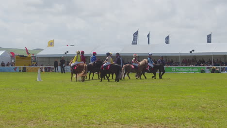 Young-Kids-Dressed-in-Colourful-Jockey-Silks-Riding-Ponies-Circling-in-Preparation-for-a-Race---slow-motion