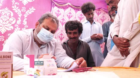 Médico-Auxiliar-Tomando-Notas-De-Refugiados-Locales-Durante-El-Alivio-De-Las-Inundaciones-En-Pakistán