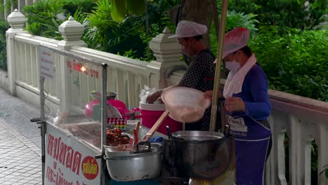 Two-women-selling-local-street-food,-small-street-stall-near-Silom,-Bangkok