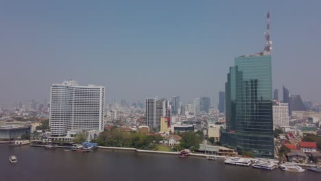 Zeitlupenansicht-Des-Chao-Phraya-Flusses-In-Bangkok,-Während-Sie-Im-Boot-Mit-Dem-Bangkoker-Higrise-Gebäude-Am-Flussufer-Sitzen