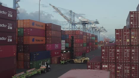 Machines-Lifting-Layers-Of-Massive-Metal-Storage-Containers-In-The-Port---panning-shot