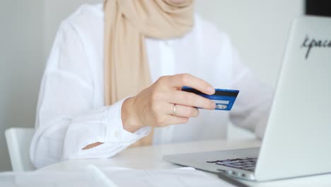 Woman-is-wearing-a-scarf-and-using-her-credit-card-for-online-shopping